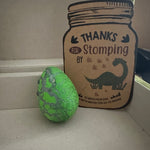 Assorted colorful dinosaur eggs arranged around a “Thanks for Stomping By” card, designed as fun hatchable toys for children’s dinosaur-themed parties.