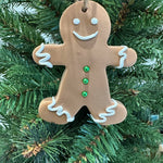Smiling gingerbread man ornament hanging on a green Christmas tree, festive holiday decoration featured in Pina Bird’s A Palm Tree’s Christmas Wish.