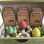 Colorful hatchable dinosaur eggs displayed in a green gift box with “Thanks for Stomping By” cards, perfect for kids’ party favors or dinosaur-themed gifts.